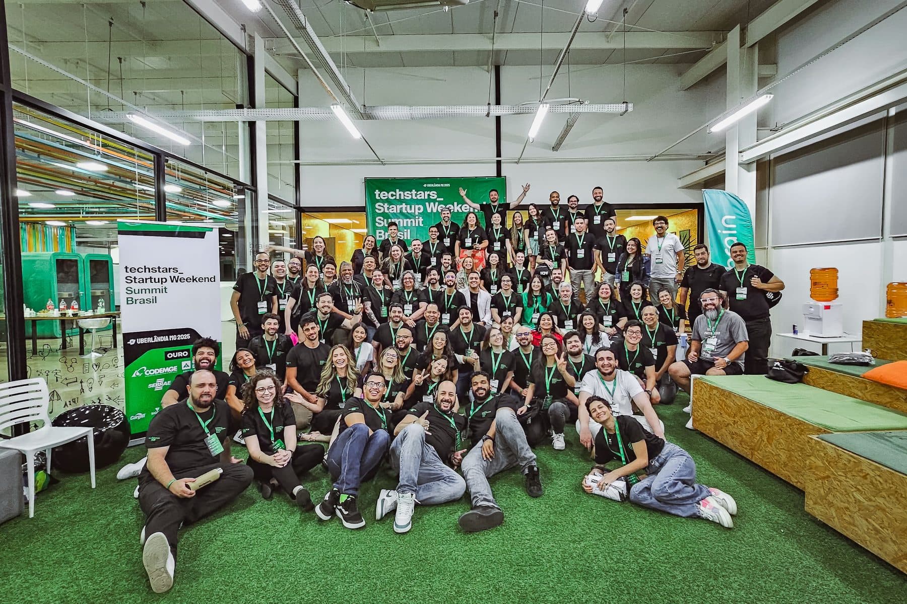 Participantes do Summit 2025 reunidos em frente ao banner do evento, no Brain